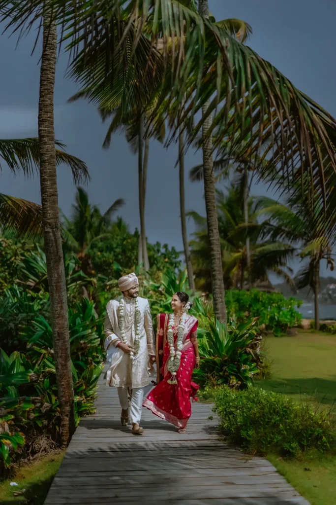 Bride and groom in traditional attire by the sea at Taj Kovalam