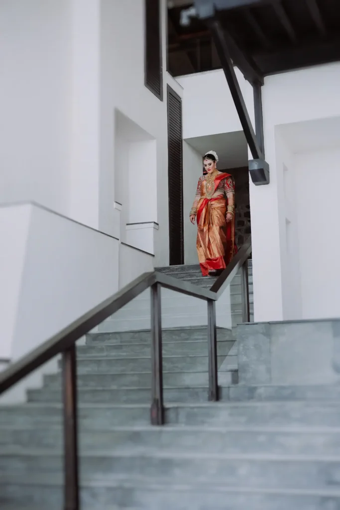 bride walking in red traditional saree at leela kovalam wedding