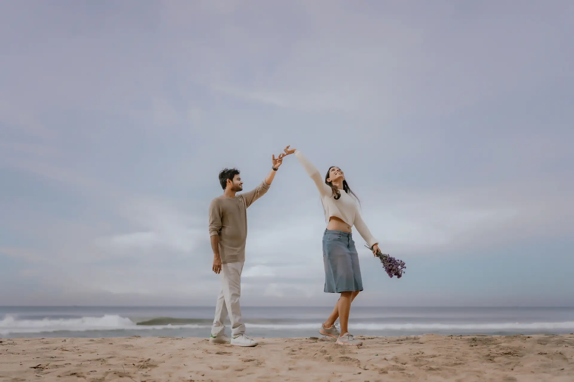 Couple holding flowers during pre-wedding photoshoot at Varkala Beach